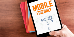 Top view of hand holding tablet with mobile friendly word- why mobile optimization matters