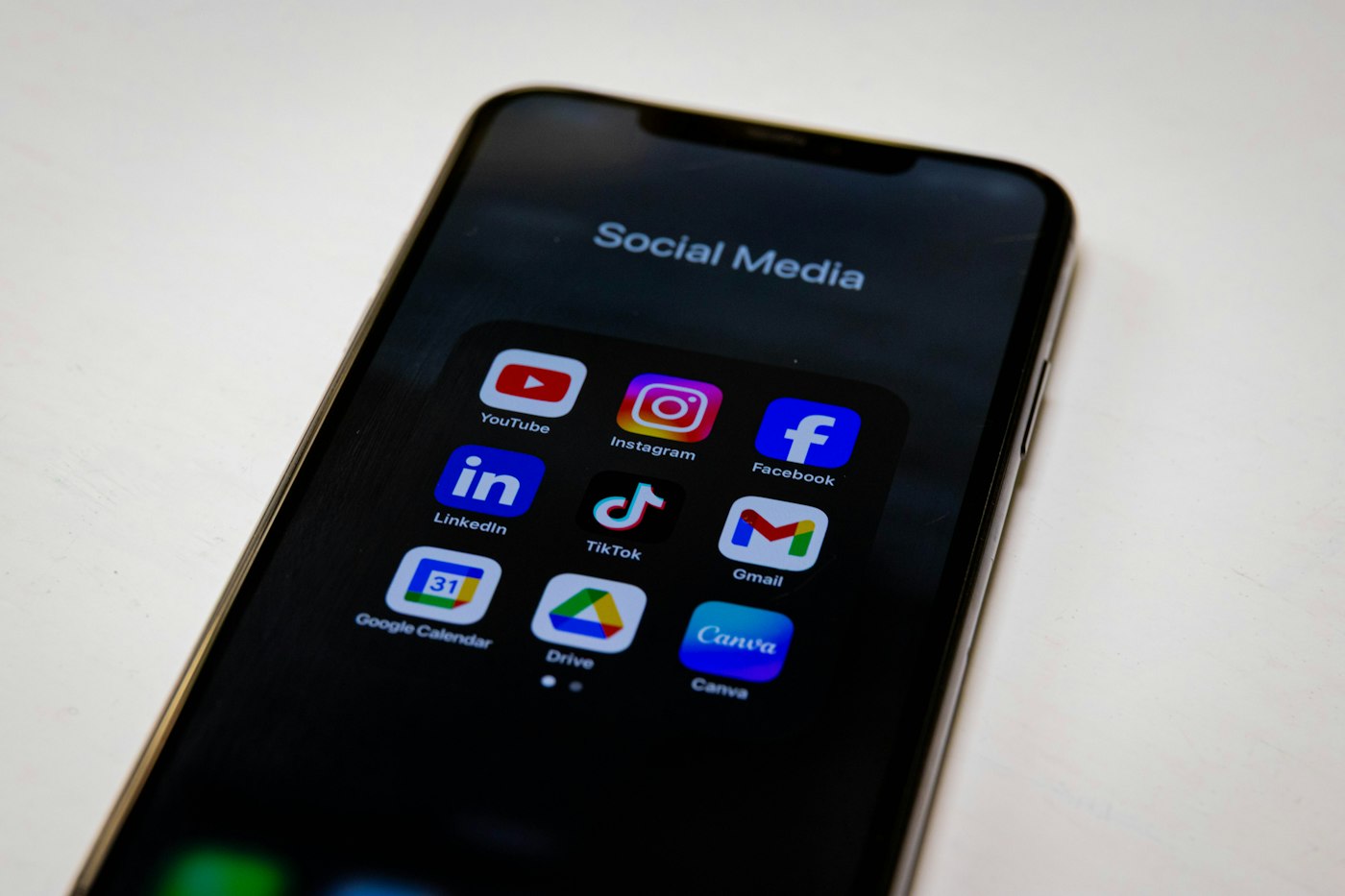Smartphone showing a social media folder with Facebook, Instagram, TikTok, LinkedIn, and YouTube apps