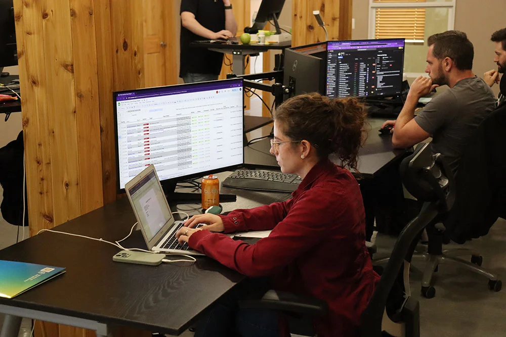 Content specialist working at a desk with a laptop and monitors