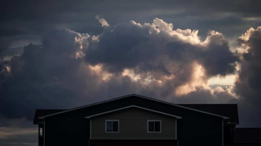 Storm clouds building over a house roofline