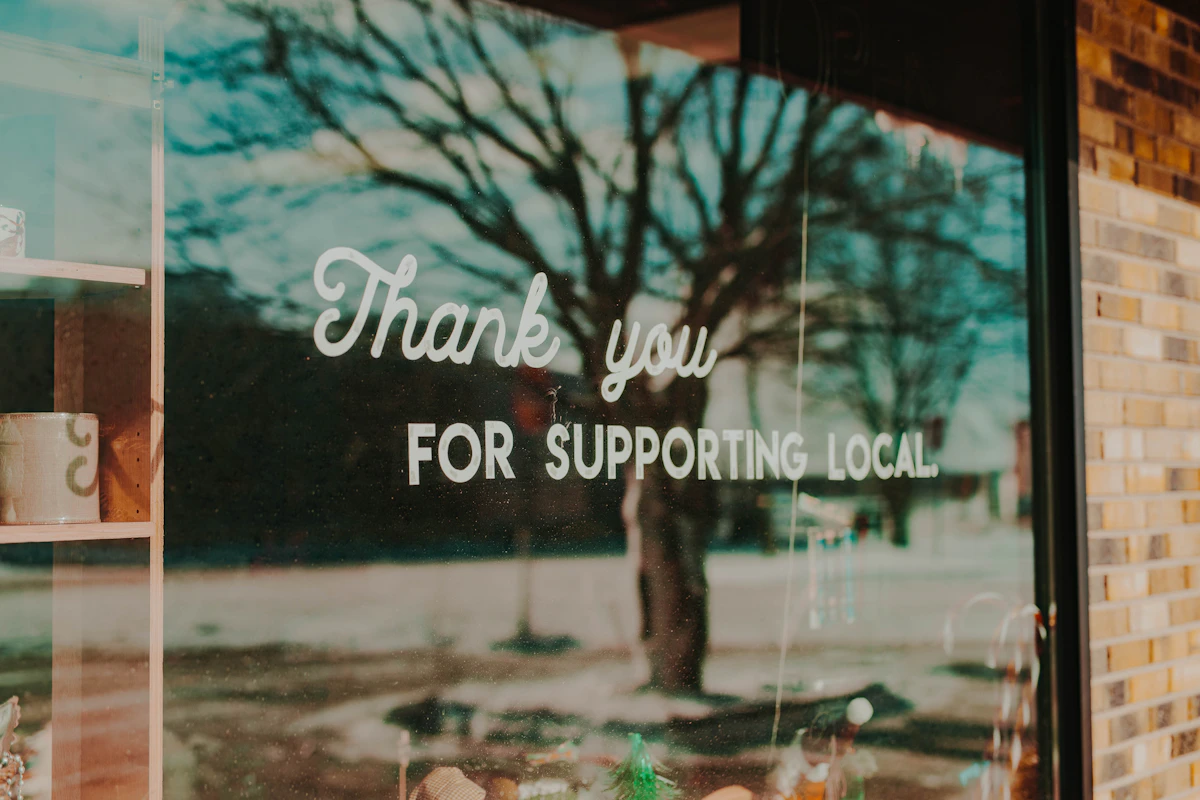 Window sign that reads Thank you for supporting local on a small business storefront
