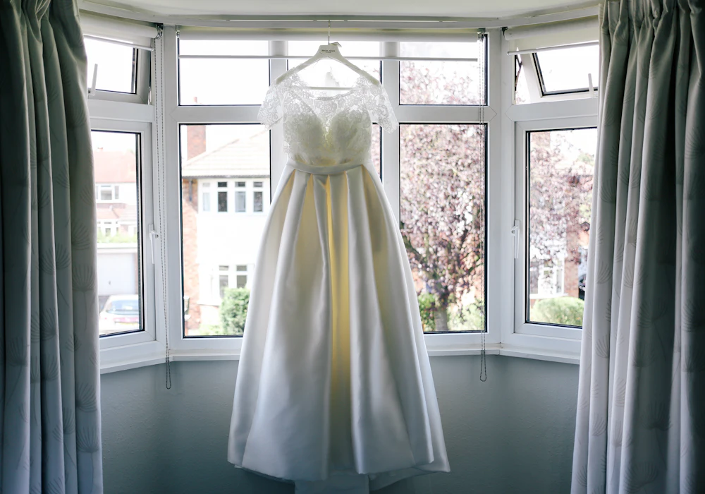 Wedding dress hanging in a bay window