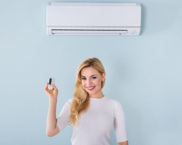 Happy woman pointing remote to ductless ac system